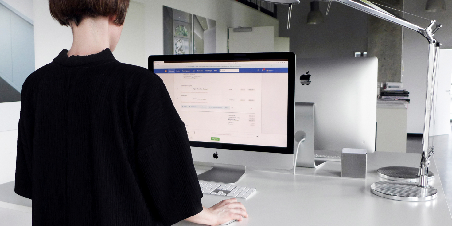 svaerm Titelbild Person arbeitet an einem iMac in einem modernen Büro mit easybill Rechnungssoftware auf dem Bildschirm