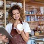 Frau verwaltet ihr Lager, Artikel und Dienstleistungen am Tablet