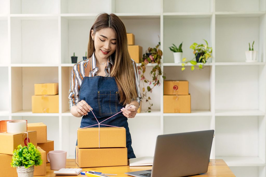 Frau schnürt Pakete fest von ihrem shopify Shop