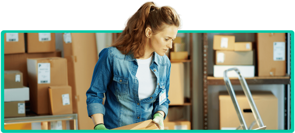 Eine Mitarbeiterin im Lager bearbeitet Pakete für den Versand, symbolisch für die Logistik im E-Commerce.