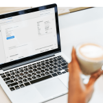 Person nutzt easybill Software zur Erstellung von Rechnungen auf einem Laptop, mit detaillierter Ansicht des Rechnungsentwurfs und einer Tasse Kaffee in der Hand.